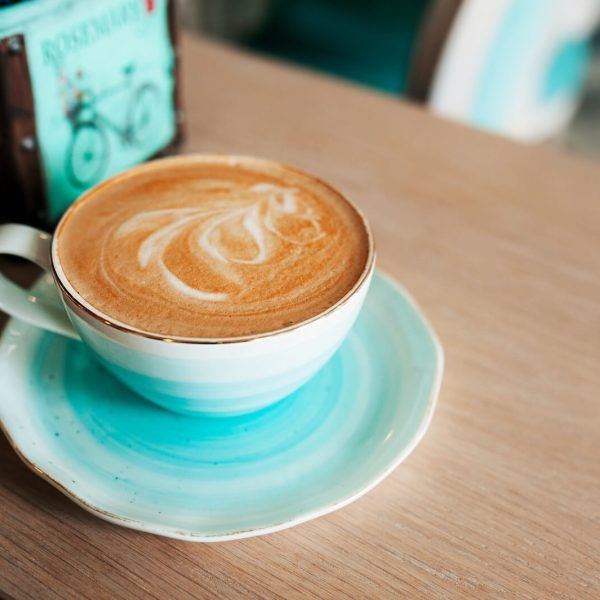 Canva - Cup of freshly brewed coffee with milk foam and a pattern in a turquoise-blue elegant porcelain mug. Grab a coffee in the beautiful light blue interior of the cafe.